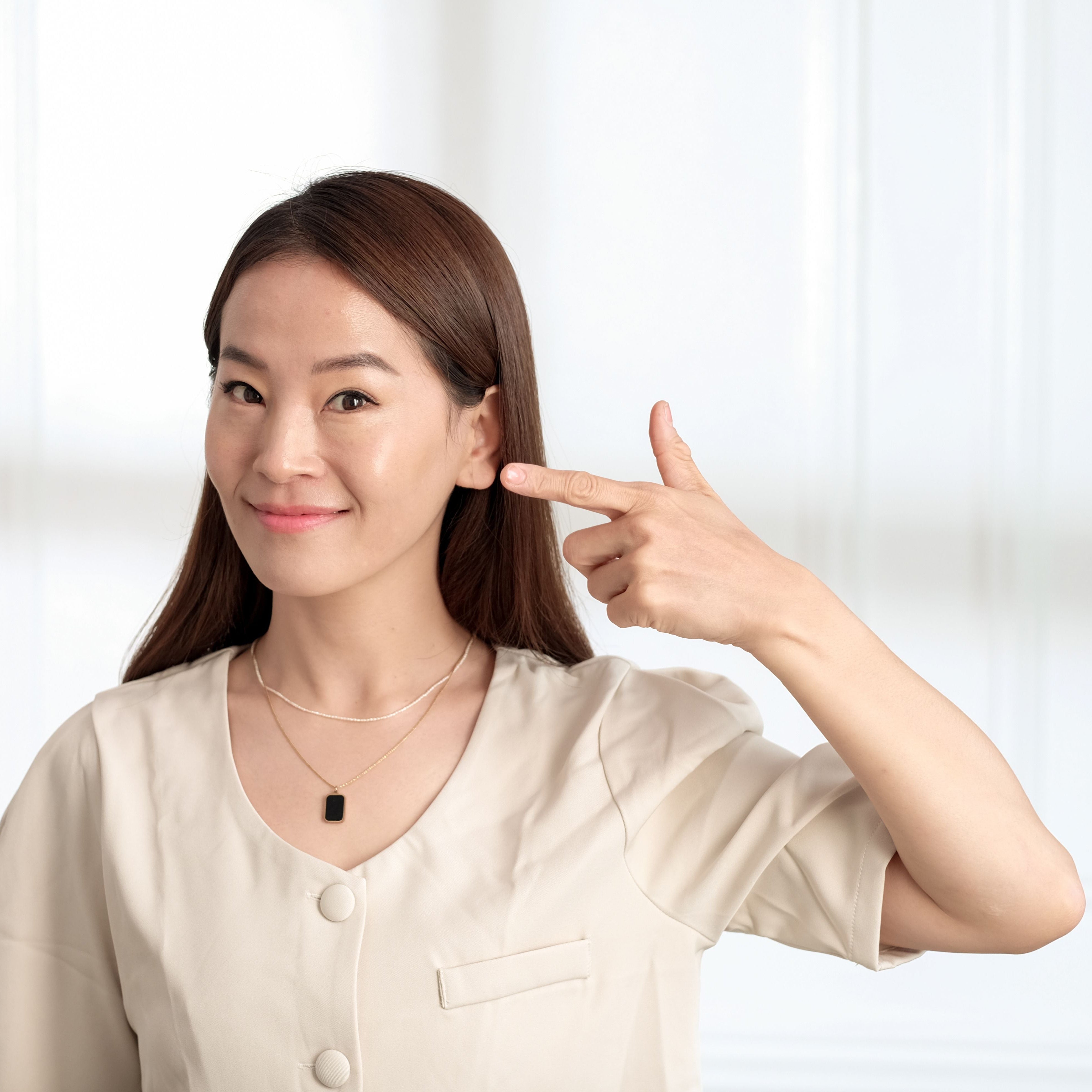 Frau zeigt auf Ihr Ohr _Neuhaus_hören_&_sehen_ratingen